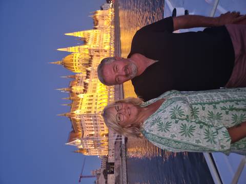 Couple posing with a lit-up historic building on a river.
