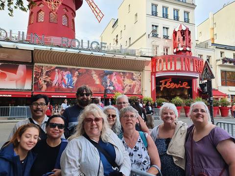 Tour group outside the Moulin Rouge, posing for a photo.