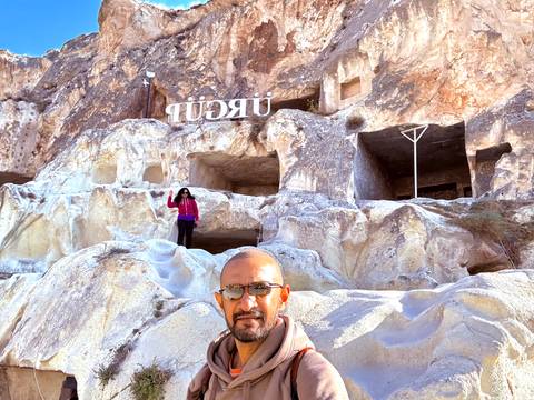       Person with caves and a sign reading 'Ürgüp'.
  