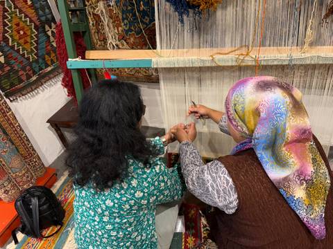       Two people engaged in traditional weaving.
  