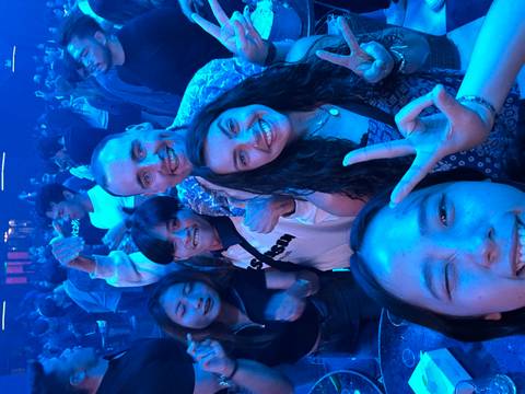       Group of people in a crowded, dimly lit club scene.
  