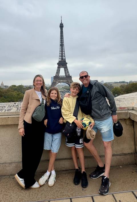       A family of four poses in front of the Eiffel Tower.
  