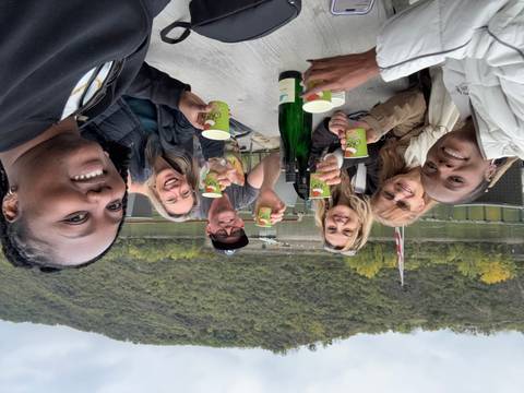 A group of people enjoying drinks at an outdoor setting with lush hills in the background.