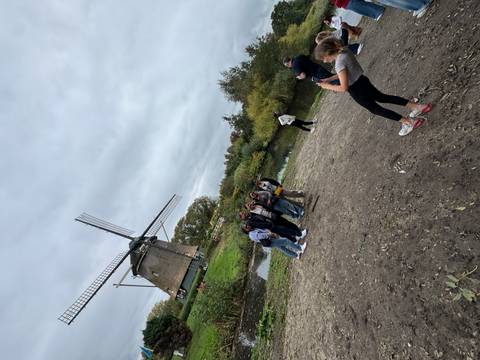       People posing near a windmill by a canal.
  