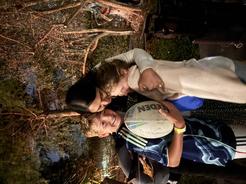       A group hug between two children and an adult at night.
  