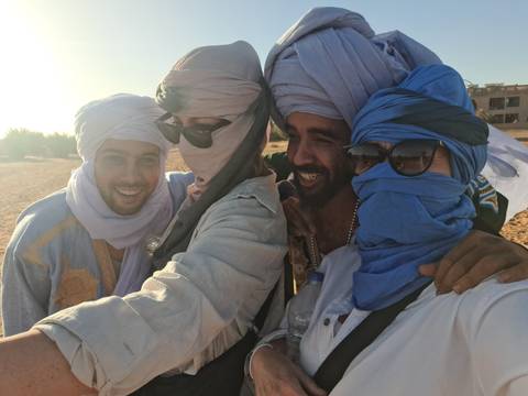       Group of people wearing headscarves taking a selfie in the desert.
  