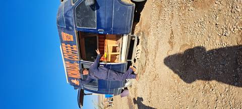       Man posing in front of a 'Nomadic Coffee' van in a desert.
  