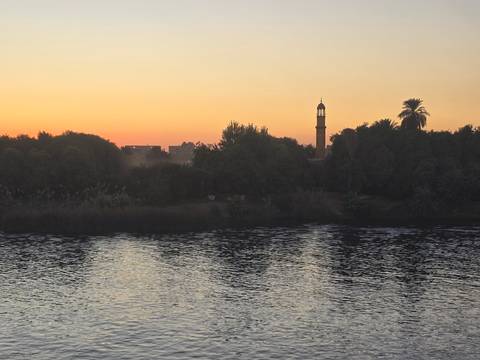       View of a riverbank and sunset sky.
  