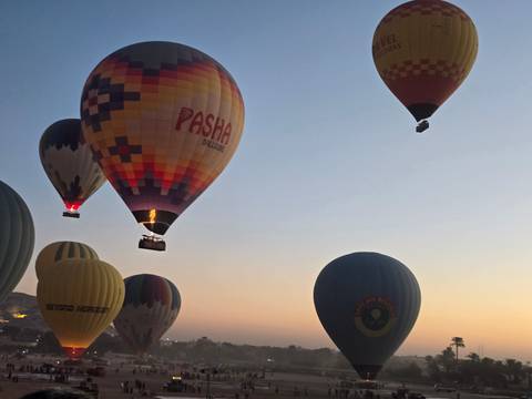 A group of hot air balloons floating in the sky at sunrise or sunset.