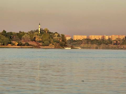 Peaceful riverside view with a mosque in the background.