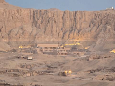       Distant view of a large archaeological site against a mountain backdrop.
  