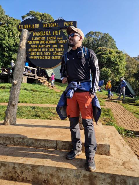 Person near a sign pointing to Uhuru Peak at Mount Kilimanjaro.