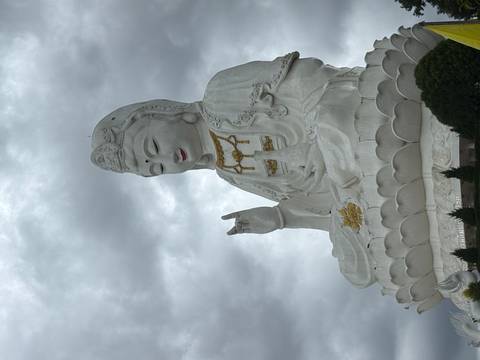 Giant statue of a seated figure against a cloudy sky.