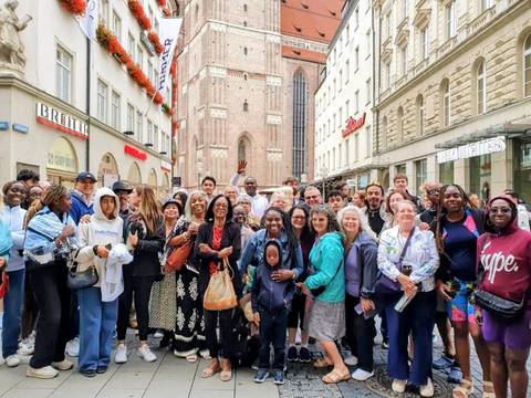 Group of tourists posing in a city street with historic buildings.