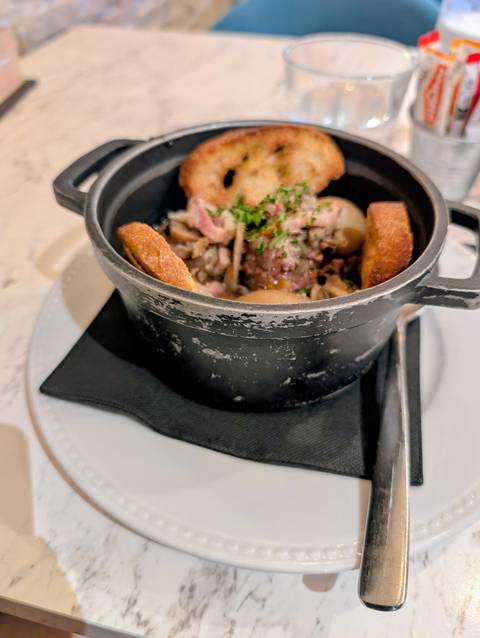 Close-up of a dish served in a black pot with visible ingredients.
