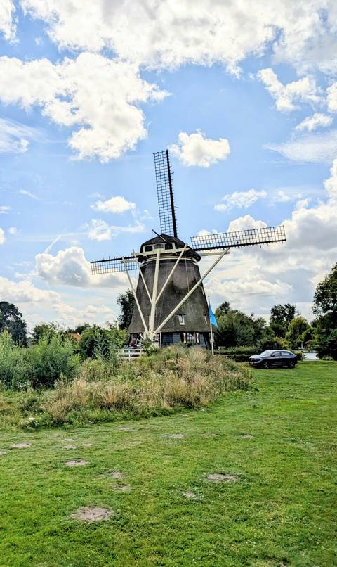 Traditional windmill in a rural setting with blue skies.
