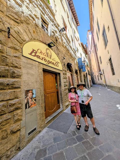 Couple posing outside a historic restaurant on a narrow street.