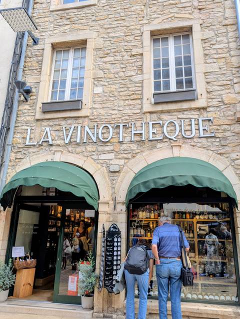 Wine shop exterior with green awning and stone walls.