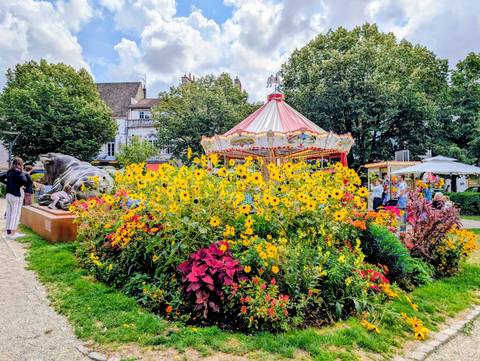 Colorful flowers surrounding a carousel in a park.