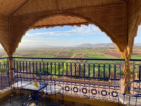 View from a balcony towards a valley with fields and mountains.