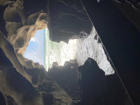 Coastal cave opening to the ocean with waves crashing in.