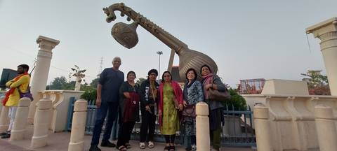       Group of people posing in front of a large sculpture resembling a musical instrument.
  