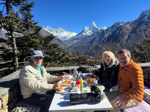       People having breakfast with a stunning mountain view in the background.
  