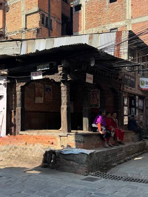       People sitting under a traditional structure in a bustling street.
  