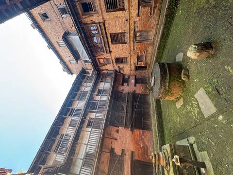       Old courtyard surrounded by traditional brick buildings.
  