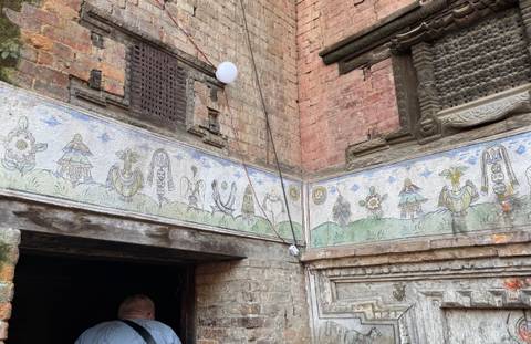      Decorative mural on a brick wall with traditional carvings.
  