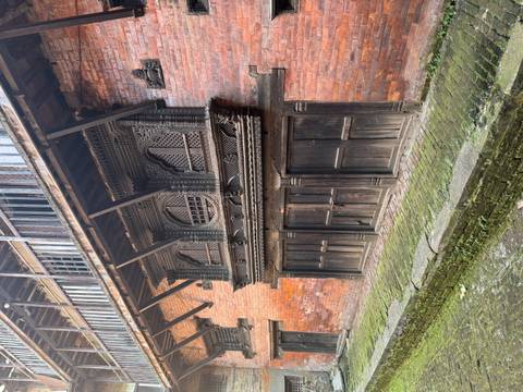       Detailed wooden balcony in a traditional brick building.
  