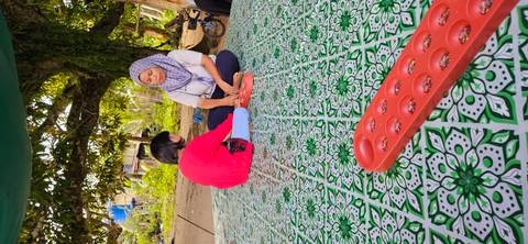 Two people playing a traditional game on a mat.