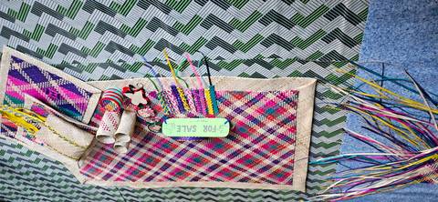 Colorful woven mats and crafts on display for sale.