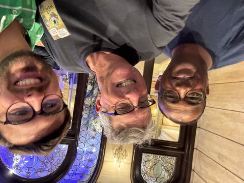       Three men smiling indoors.
  