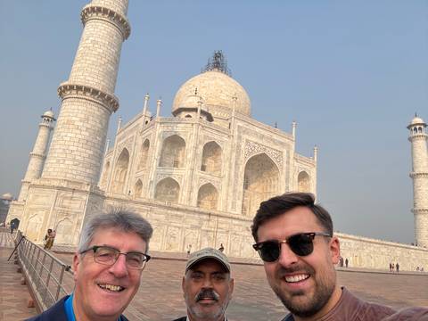       Closeup of three men in front of the Taj Mahal.
  