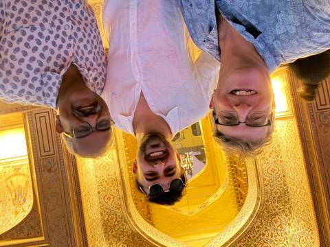       Three men smiling in a beautifully decorated entrance.
  