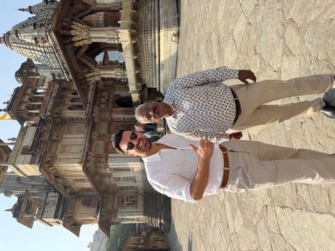       Two men posing in front of an intricate building.
  