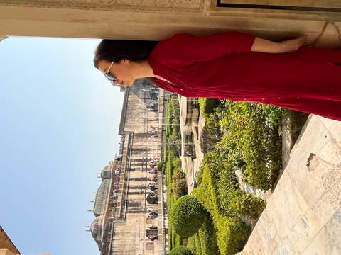       Woman posing by a column with historical architecture.
  
