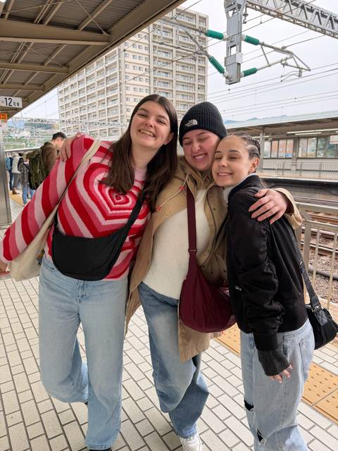 A group of three people smiling at a train station.