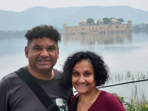       Couple posing in front of a palatial building by a lake.
  