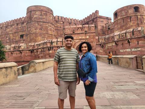 Couple posing in front of a large red fort.