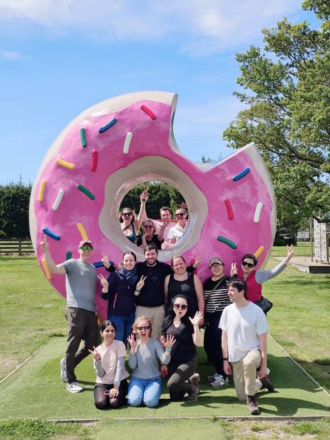 Group of people posing with a large doughnut sculpture