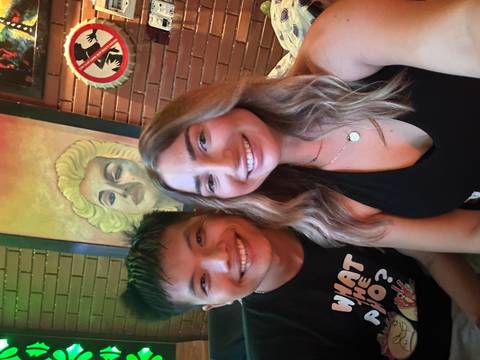 Portrait photo of two people with a painting in the background.