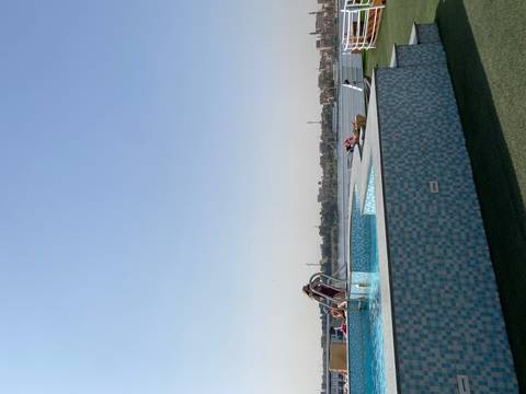       People relaxing by a pool with river view.
  