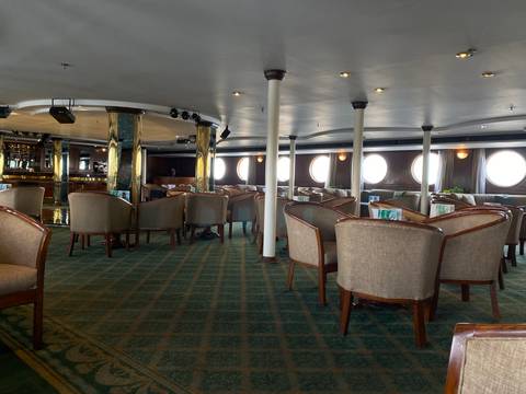 Interior of a ship's lounge with lots of seating.