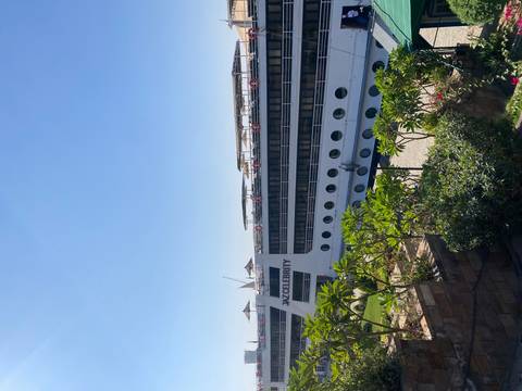 View of a cruise ship named 'Jaz Celebrity' docked by the shore.