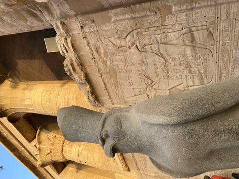 Statue of Horus and Egyptian hieroglyphic wall relief at a temple.