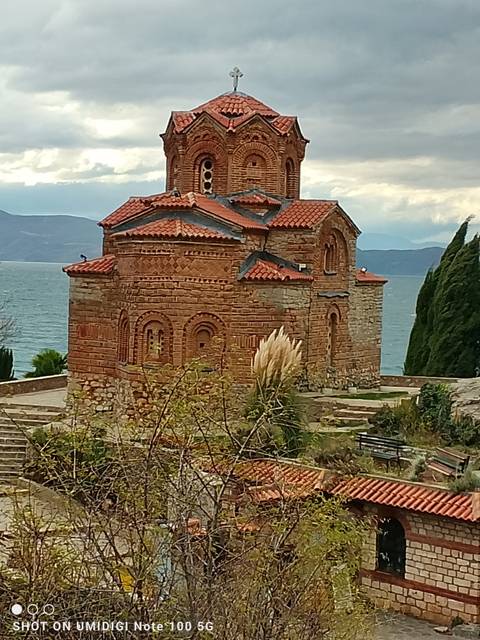       Historic church overlooking a lake with mountains in the background.
  
