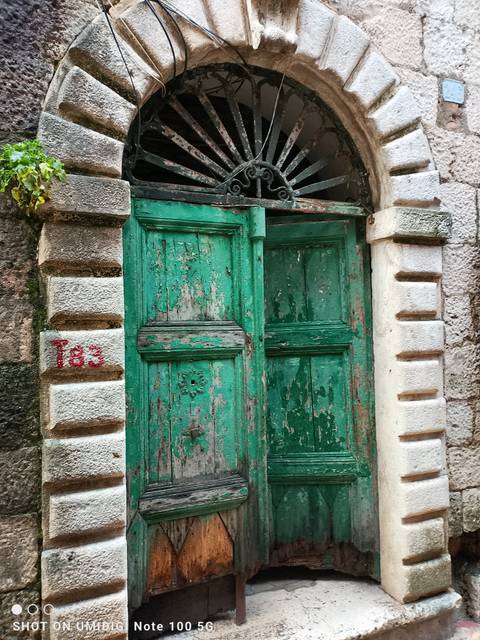       Weathered wooden door with stone wall.
  