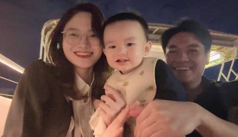 A family of three posing with a nighttime backdrop on a boat.